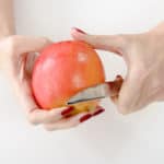 53887958 – hands of young woman peeling an apple, isolated on white